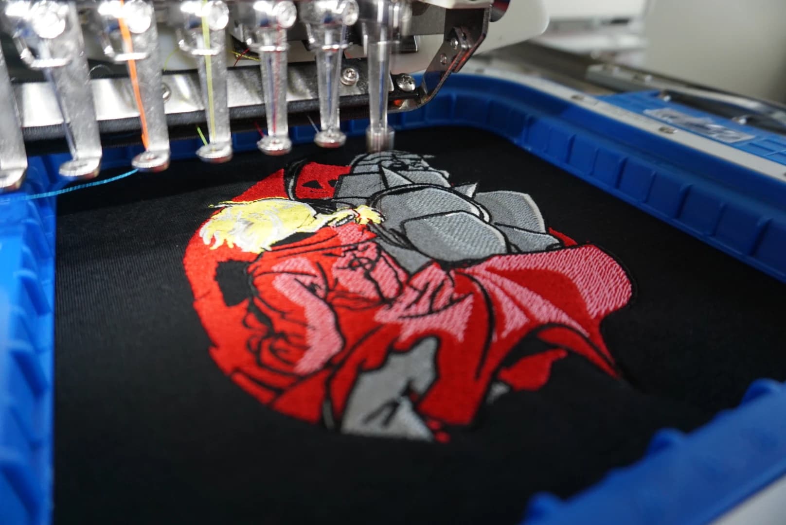 Embroidery machine stitching a colorful design in a blue hoop
